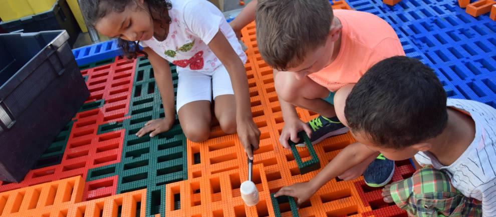 Kinder bauen gemeinsam mit Legosteinen und Hammer eine riesige Lego Pyramide